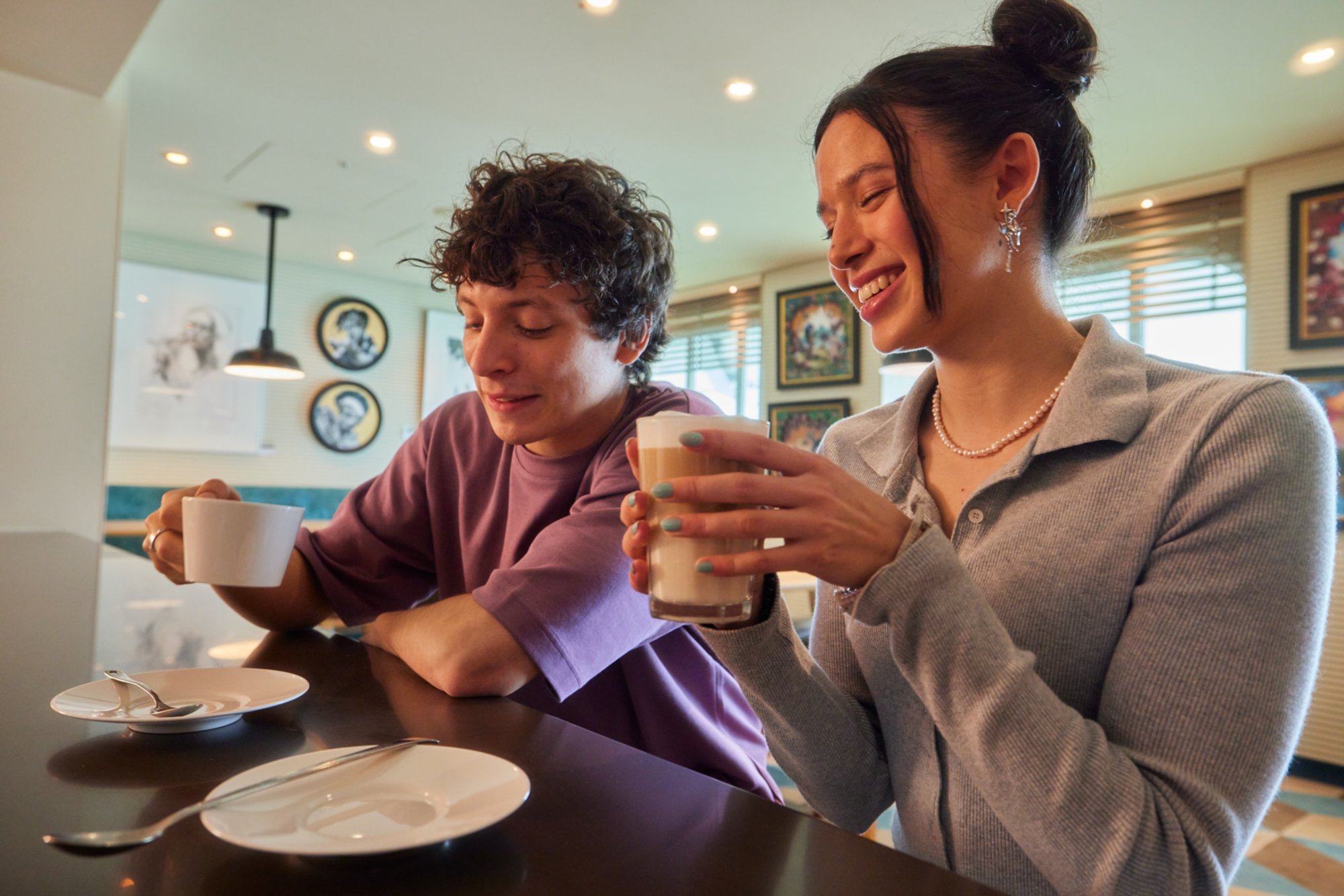 Zwei Personen genießen Kaffee in der stilvollen Art Bar mit moderner Kunst an den Wänden.