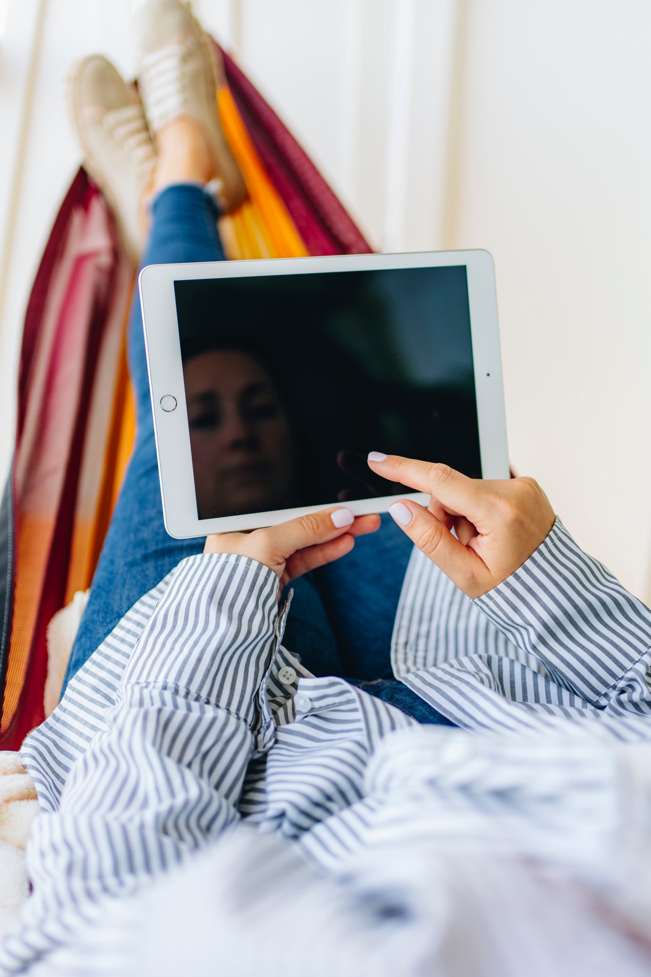 Frau liegt mit Tablet in der Hängematte