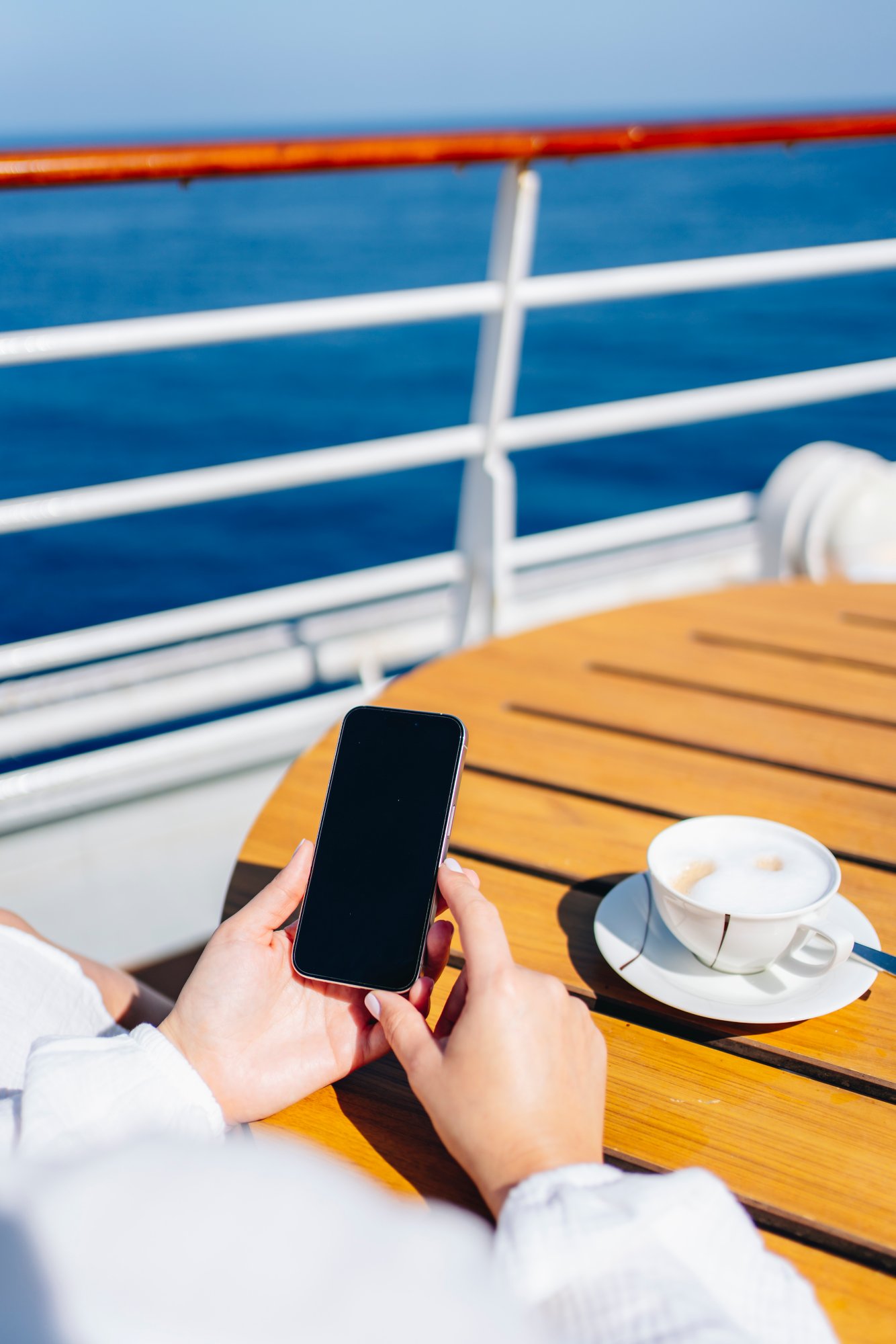 Hände halten Smartphone auf dem Deck