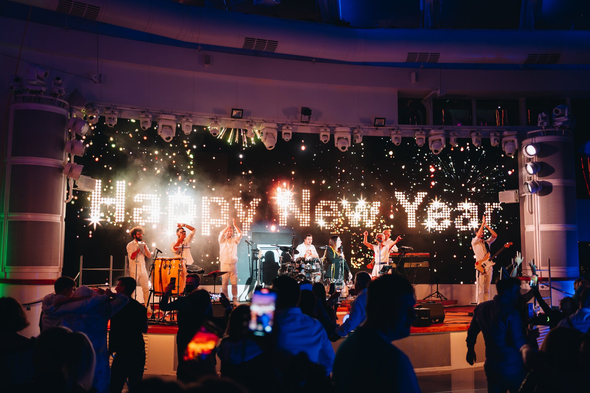 Ein einer Wand steht groß Happy New Year und davor steht eine Band und macht Musik