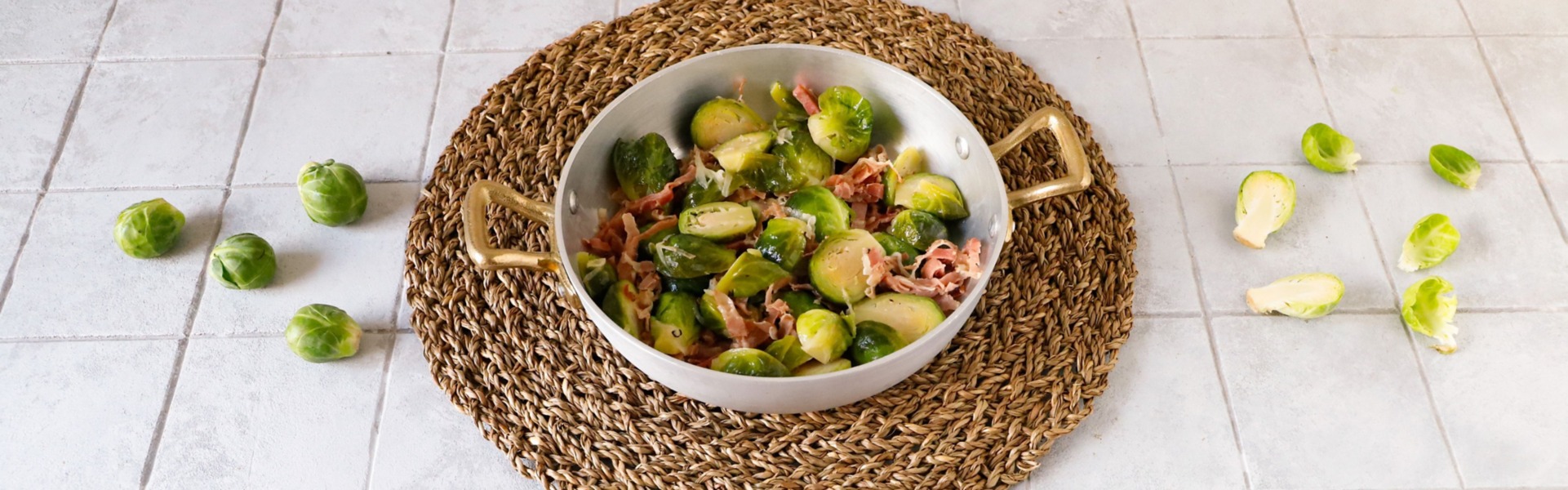 Colorati cavoletti di Bruxelles serviti con speck a listarelle in un elegante padellino