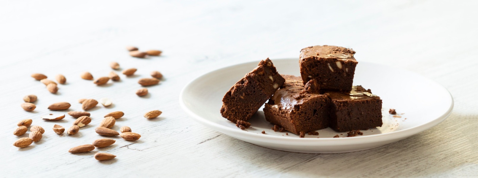 Irresistibili brownies alle mandorle e cioccolato fondente adagiati su un piatto bianco