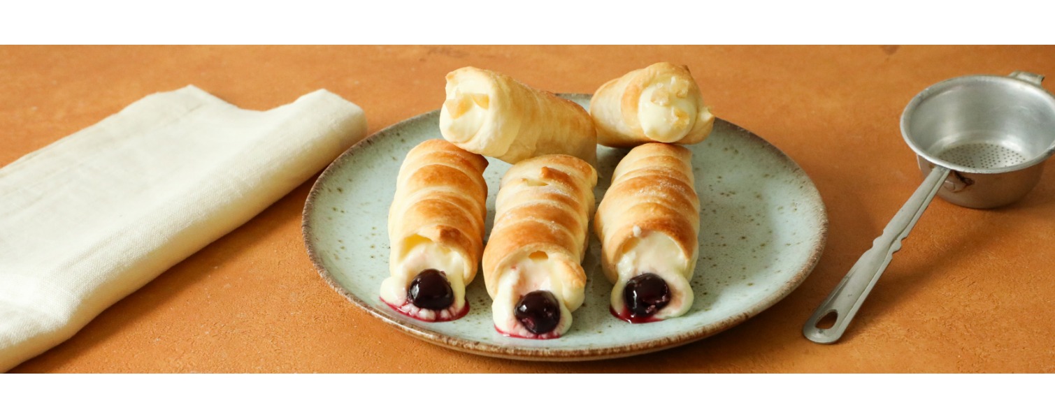 Su un piatto sono serviti i cannoncini farciti con una invitante crema e una succosa amarena