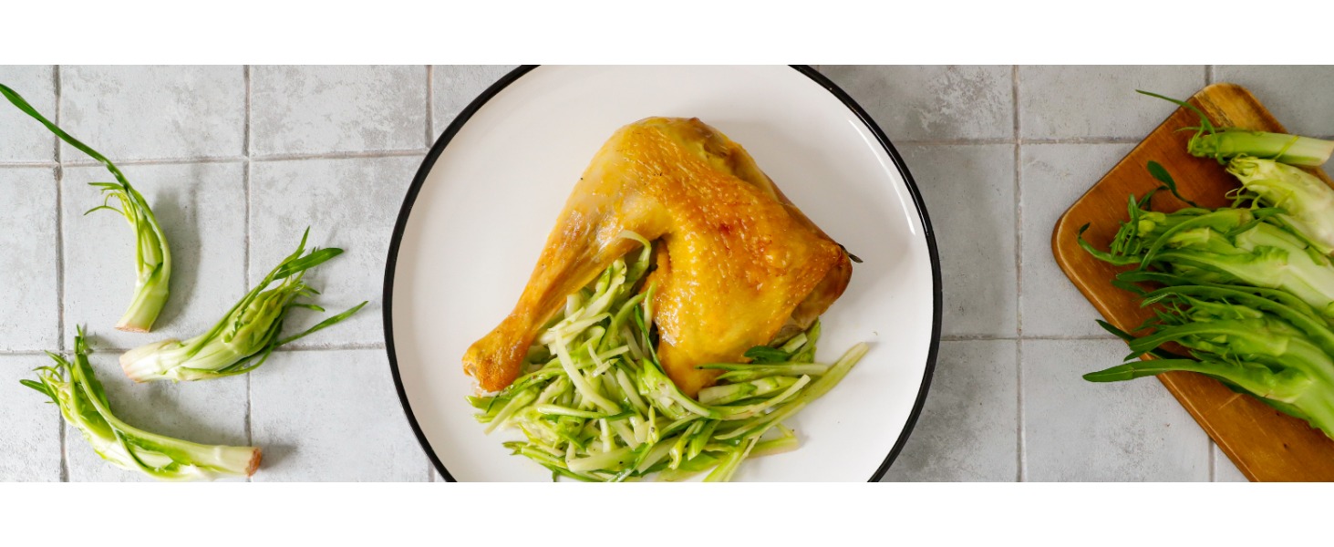 Su un piatto bianco è servita una coscia con sovraccoscia di cappone dorata, con un contorno di puntarelle tagliate finemente