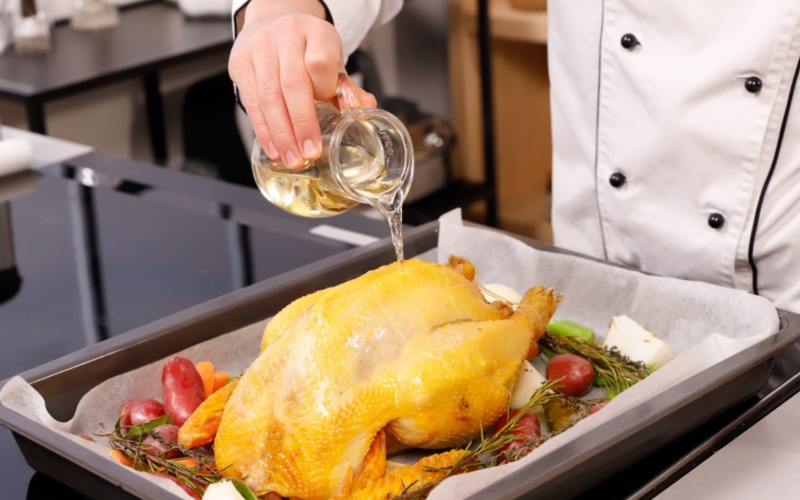 Bagnare il cappone ripieno con il vino bianco e cuocere in forno