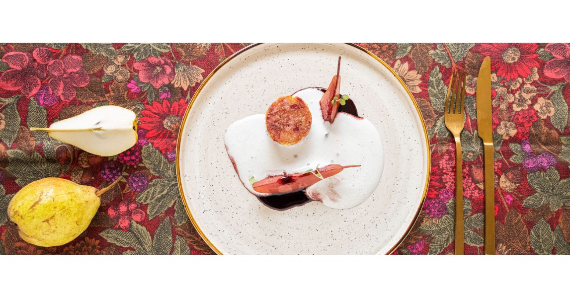 Il piatto mostra il cotechino servito con pere e coperto da una densa crema bianca di pecorino