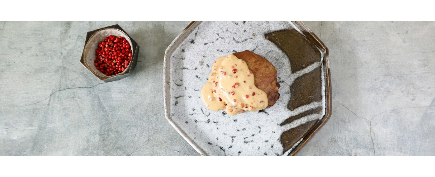 Il filetto al pepe rosa è servito su un elegante piatto con una salsa con grani di pepe rosa