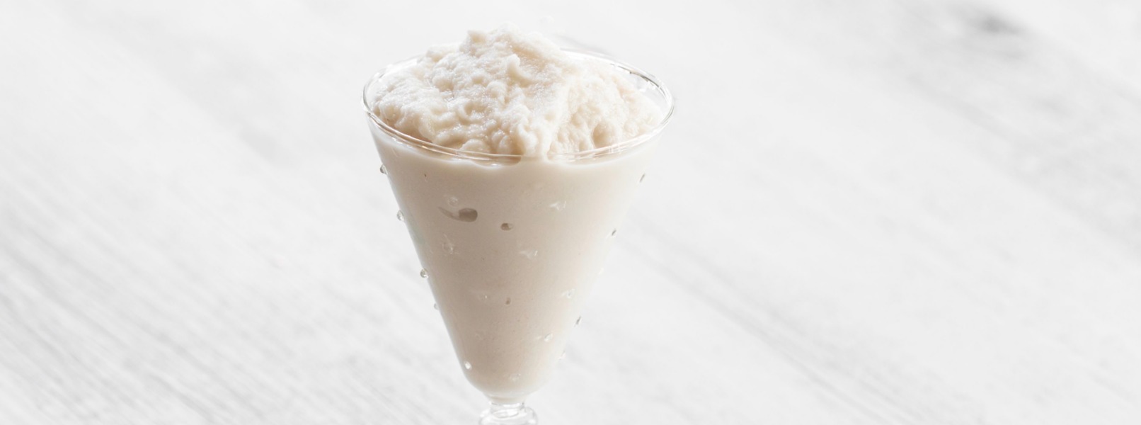 Una fresca e invitate granita siciliana alle mandorle è servita in un bicchiere di vetro trasparente che invoglia all’assaggio