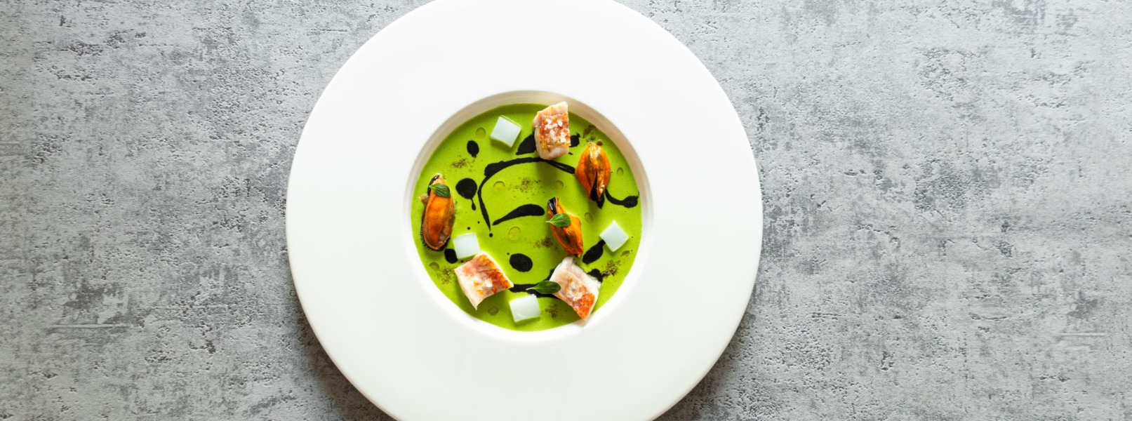 Triglia, cozze e seppie sono immerse in una crema verde con schizzi di condimento