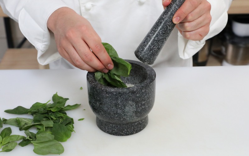 Basilico nel mortaio per il pesto genovese