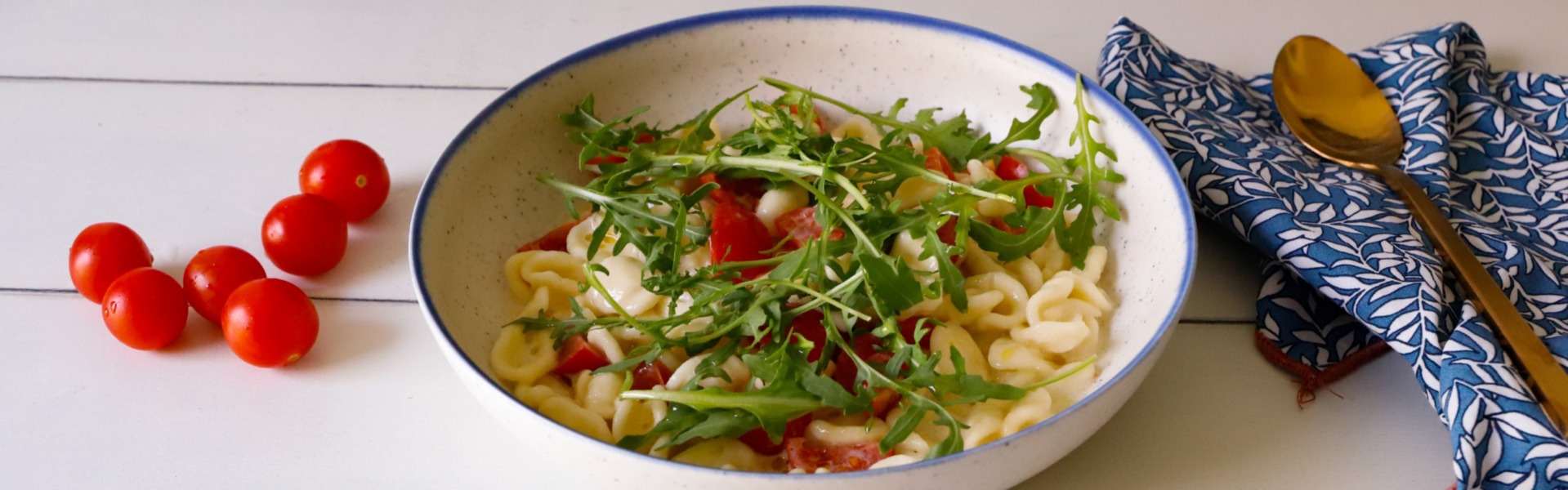 Orecchiette alla crudaiola su un un piatto al centro della tavola imbandita