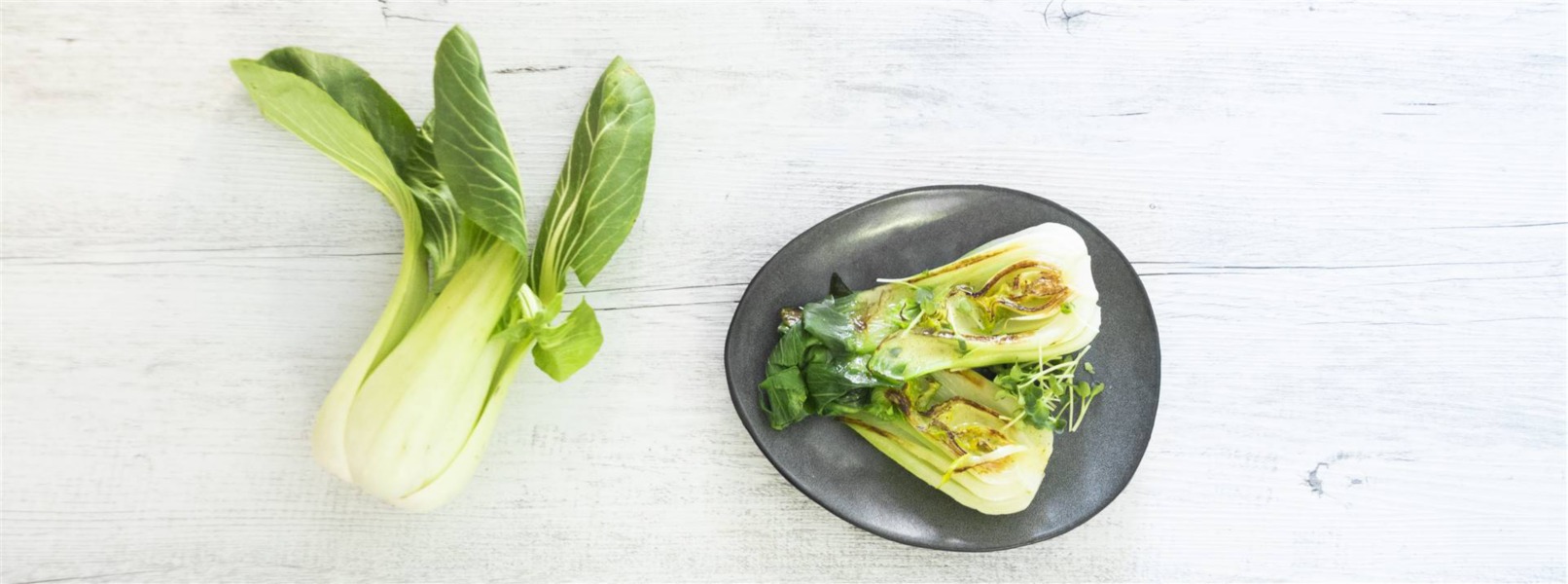 In un piatto è servito un pak choi tagliato a metà, grigliato e condito con salsa al cocco e curry