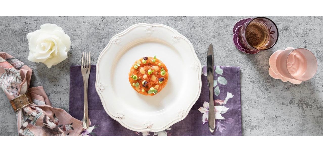 La millefoglie di salmone, rotonda e ordinata, spicca arancione con ciuffi di salse verdi e aranciate