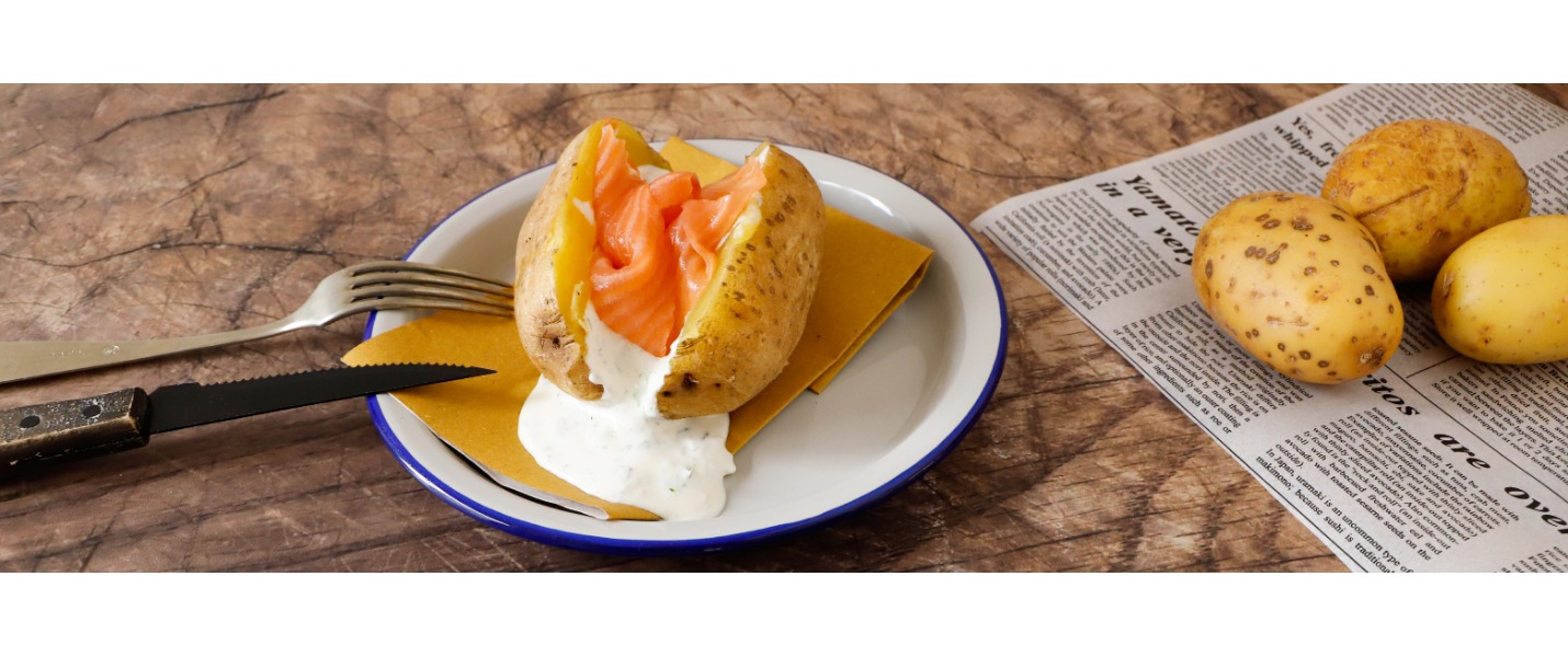 Lo street food servito al piatto, con una patata cotta e tagliata a metà, farcita con una fetta di salmone affumicato e un’invitante panna acida. 