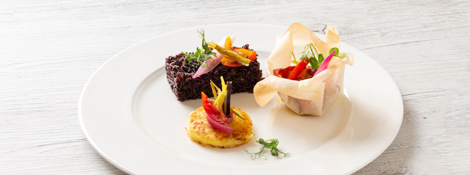 Un cubetto di riso venere accompagnato da un tortino di patate ed un cestino di pasta brick