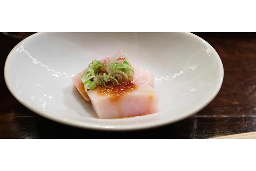 Un piatto di crudo di pesce spada a cubetti, con salsa agrodolce di cipolle, porro tagliato a rondelle e salsa di soia