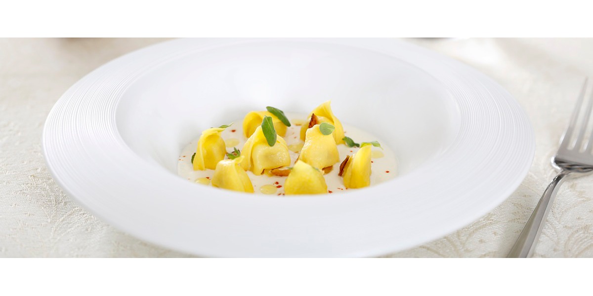 Tortellini di Modena su fonduta di Parmigiano Reggiano con cipolla croccante