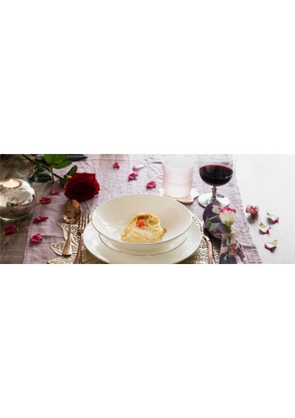 Un’elegante tavola imbandita con al centro un piatto di spaghettini con spolverata di bottarga e uova di salmone