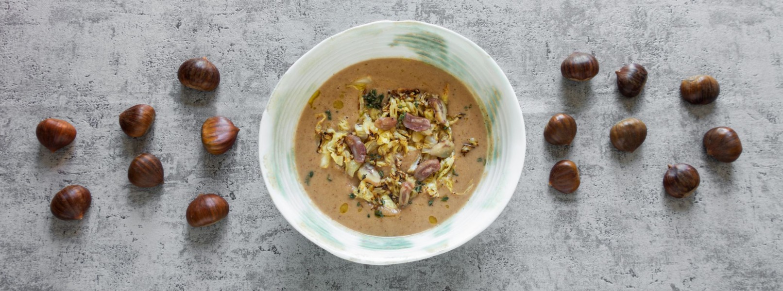 Zuppa di verza e castagne in un piatto bianco a centro tavolo con castagne