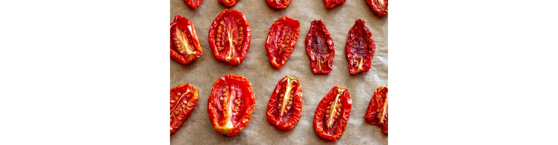 Rossi pomodori secchi con i semi gialli disposti su un tavolo al sole