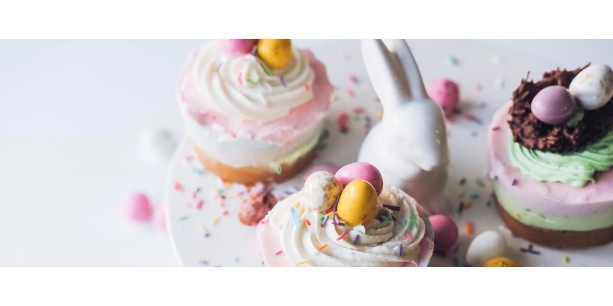Un muffin con la crema bianca e coriandoli zuccherati sulla cima è posato sul tavolo vicino un coniglio decorativo