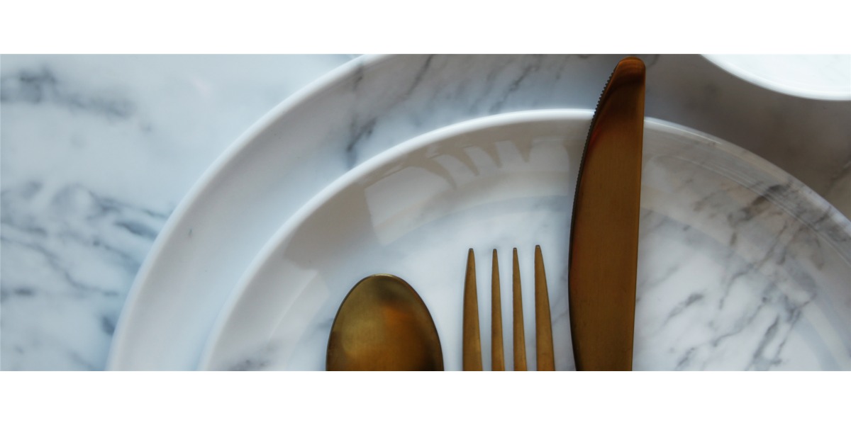 Su piatti bianchi dalle venature marmoree, sono poste in modo preciso e attento le posate, secondo le regole del galateo a tavola