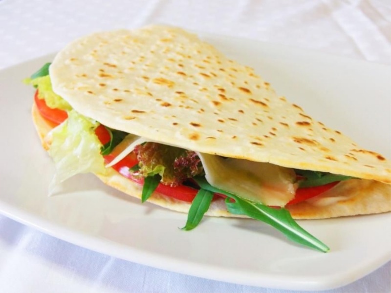 Piadina con robiola fresca, rucola e petali di asiago nero Dop