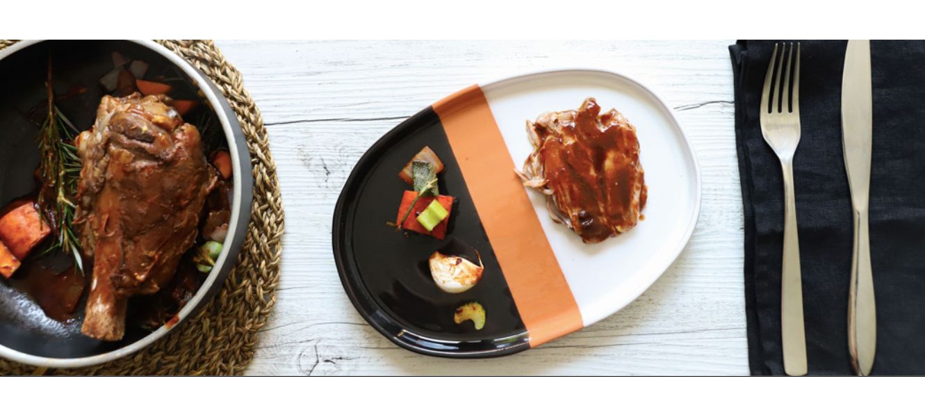 Stinco di maiale al forno con senape e aromi disposto su un piatto decorato con verdure di contorno