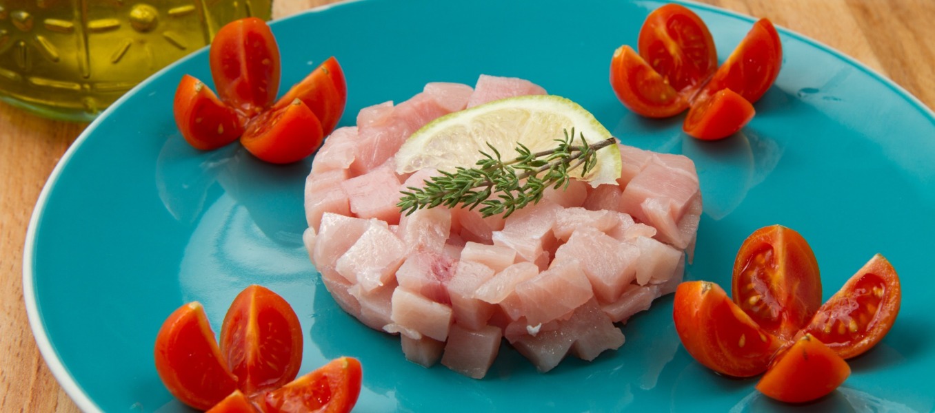Tartare di pesce spada mela verde e cipolla rossa servita su un cucchiaio ed accompagnata da cubetti di mela