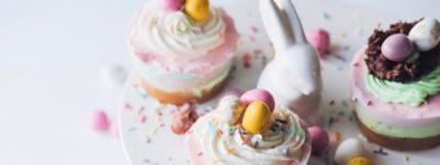 Un muffin con la crema bianca e coriandoli zuccherati sulla cima è posato sul tavolo vicino un coniglio decorativo