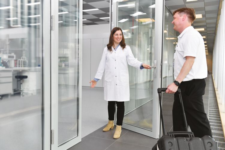 male service engineer with service tool box in his hand walks in the customer lab, female operator, meeting customer, repair