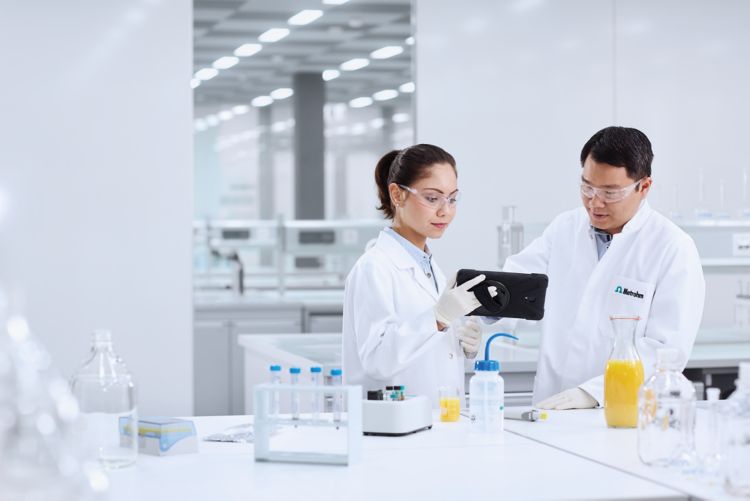 Two researchers in a laboratory testing food samples with MISA and checking the results on a tablet.